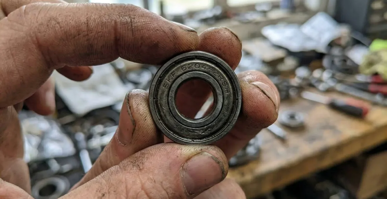 Gros plan sur un roulement tenu par des doigts montrant le marquage de référence gravé sur la bague extérieure